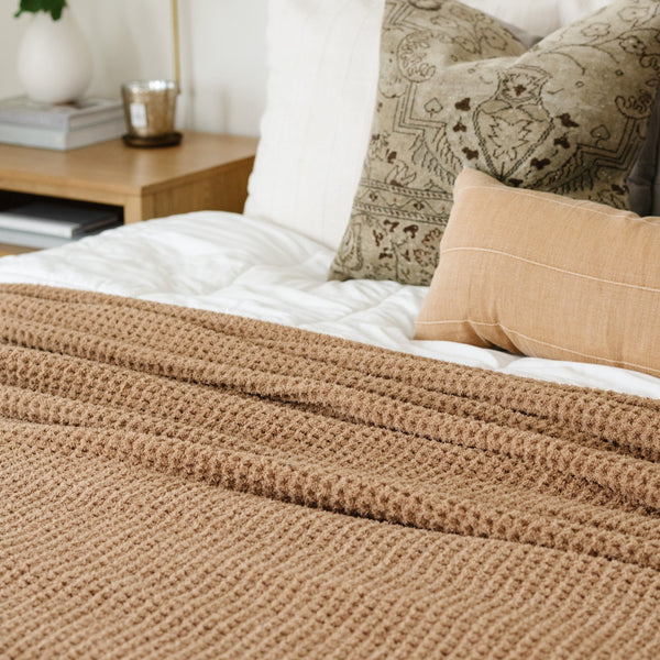 Intricate details of a cozy, snuggly, tan waffle knit blanket. 