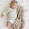 Baby girl sleeping peacefully with a tan waffle knit blanket.