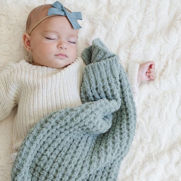 Little girl peacefully sleeping with a blue waffle knit blanket.