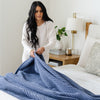 Blue-colored, queen-size waffle knit blanket shown elegantly on a bed. 