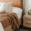 Detail shot of a caramel-colored, queen-sized waffle knit blanket with a soft, textured weave for added warmth.