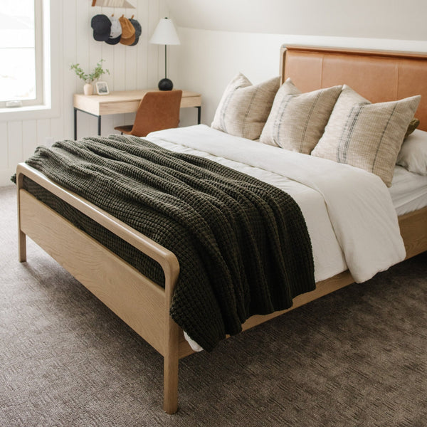 Queen bed decorated with the elegant, green, waffle knit blanket featuring a classic, grid-like pattern.