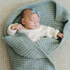 Sleeping baby wrapped up in blue receiving waffle knit blanket.