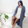 Woman in luxurious bathroom wearing cozy, blue waffle knit robe. 