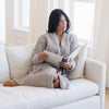 Woman sitting on couch wrapped in gray waffle knit robe.