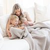 Mother and son enjoying time together on couch while wrapped in light gray waffle knit throw blanket.