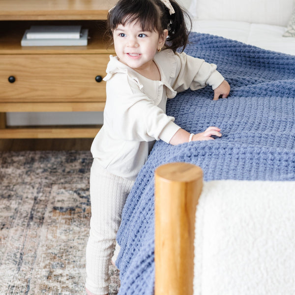 Intricate details of a blue, twin-sized blanket draped gracefully over a bed. 