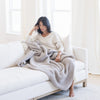 Woman relaxing on couch with grey waffle knit X blanket.