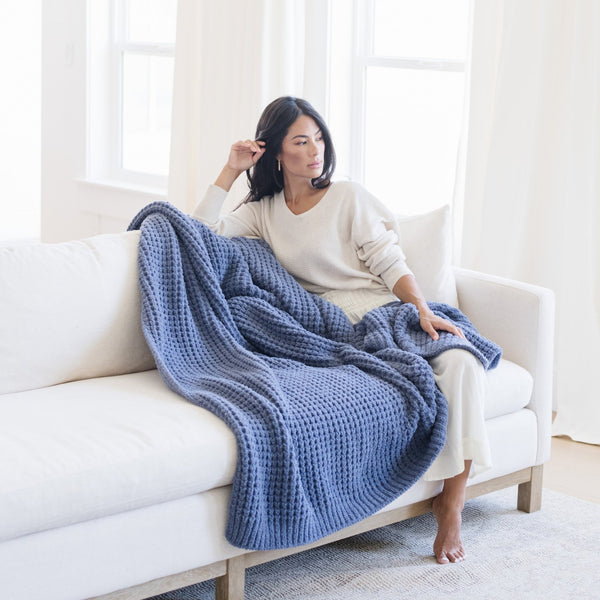 Woman relaxing at home with blue waffle knit blanket.