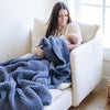 Mom and baby wrapped in blue waffle knit blanket. 